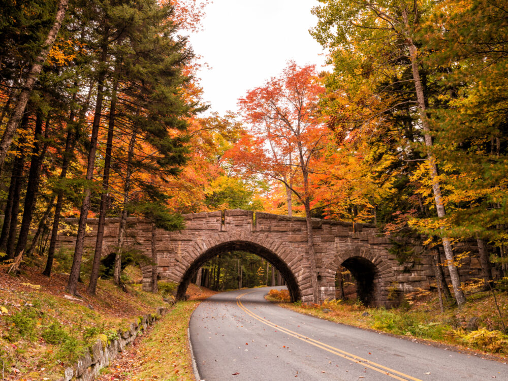 Gorgeous bridge with fall colors during the cheapest time to go to Maine, in Autumn