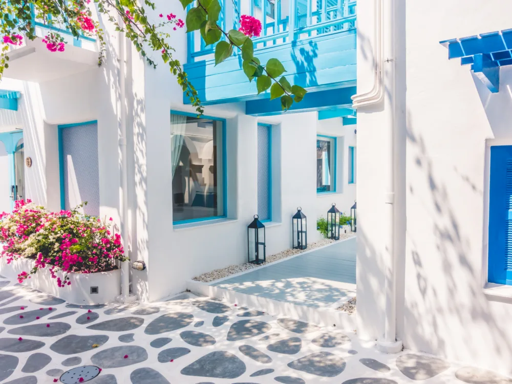 Cool blue and white architecture on a stone street pictured during the cheapest time to visit Santorini