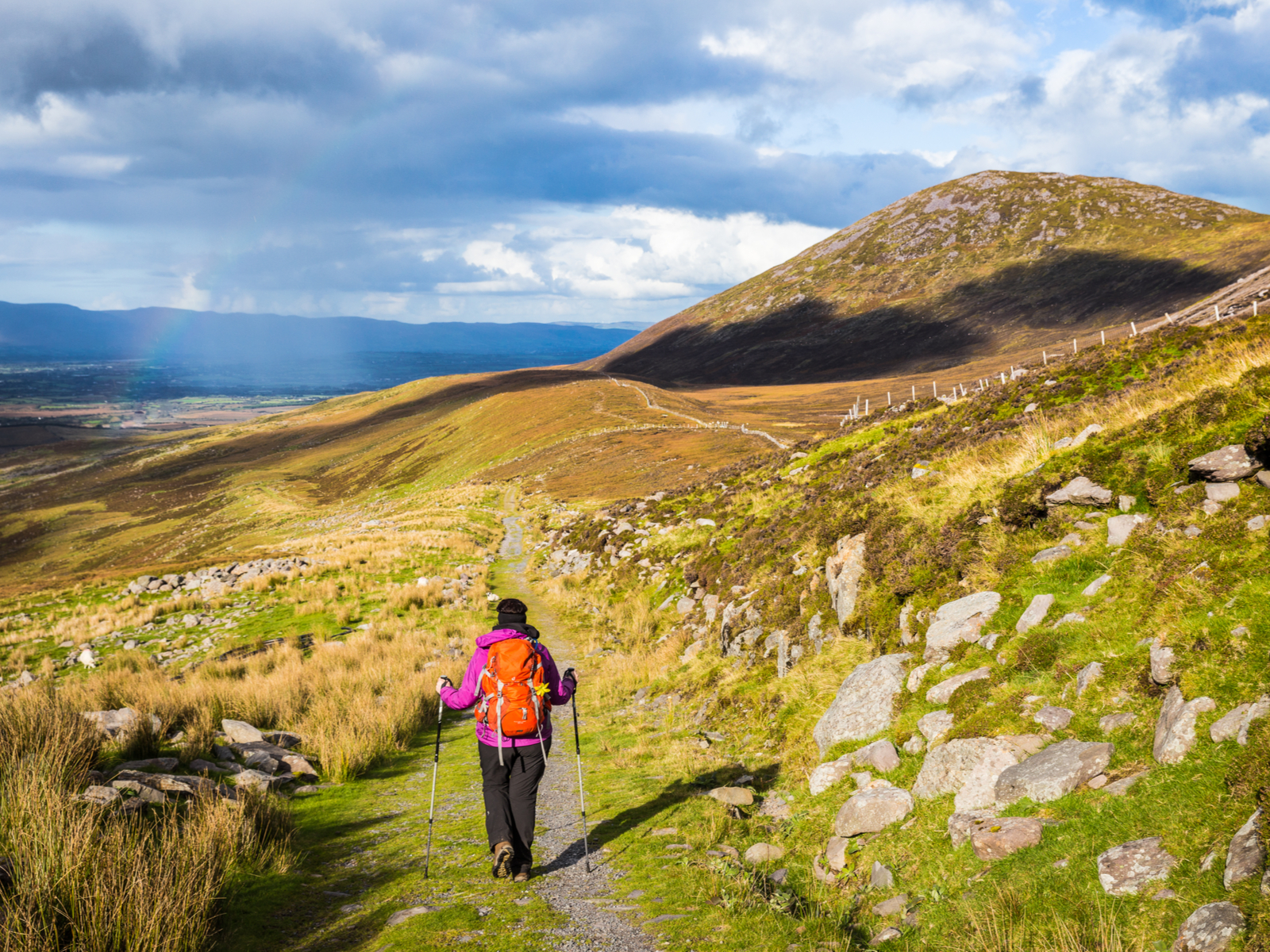 Woman doing one of the best hikes in Ireland with poles and a day pack