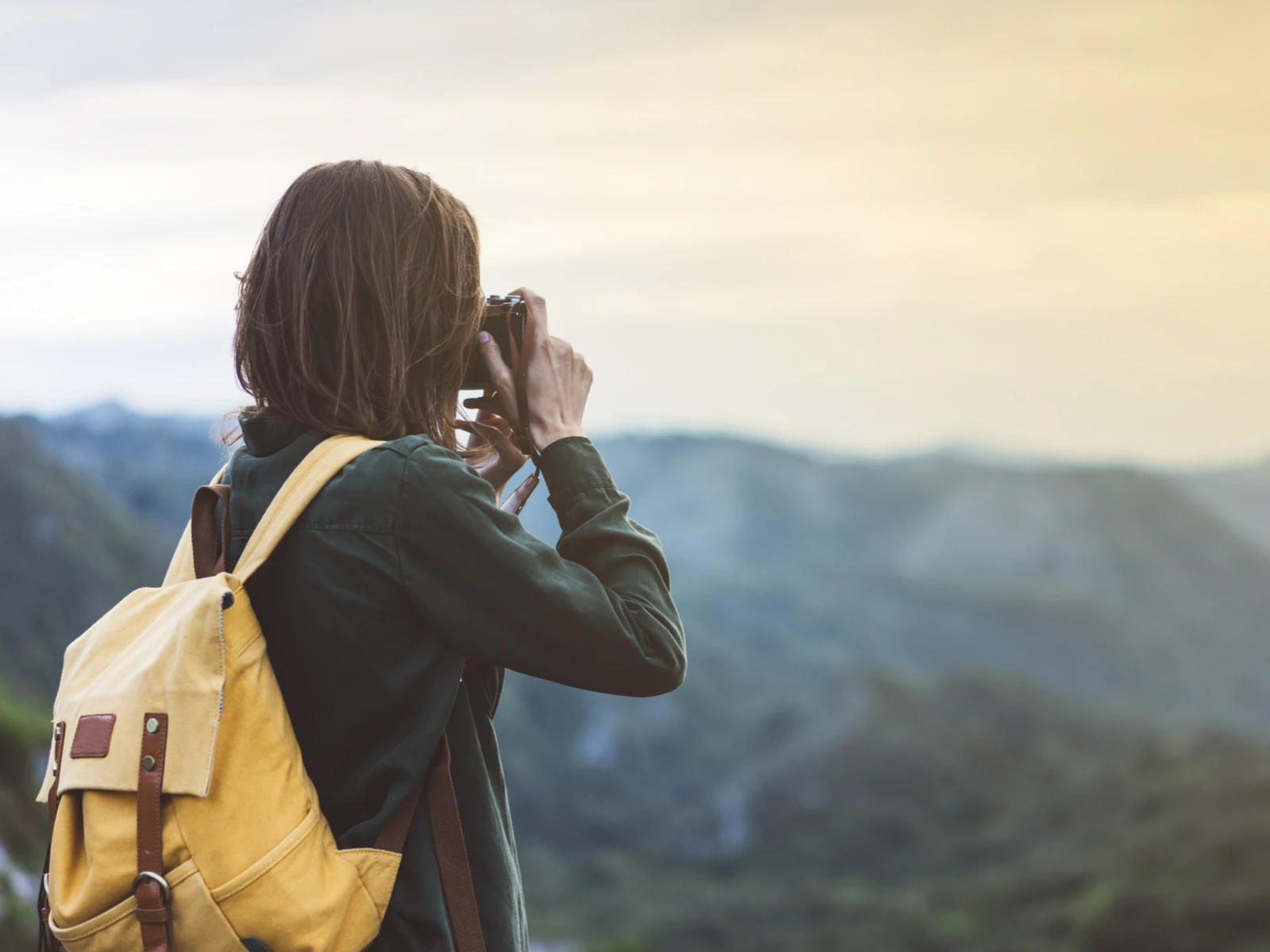 Woman with dark hair using the best travel camera to take a photo of a valley