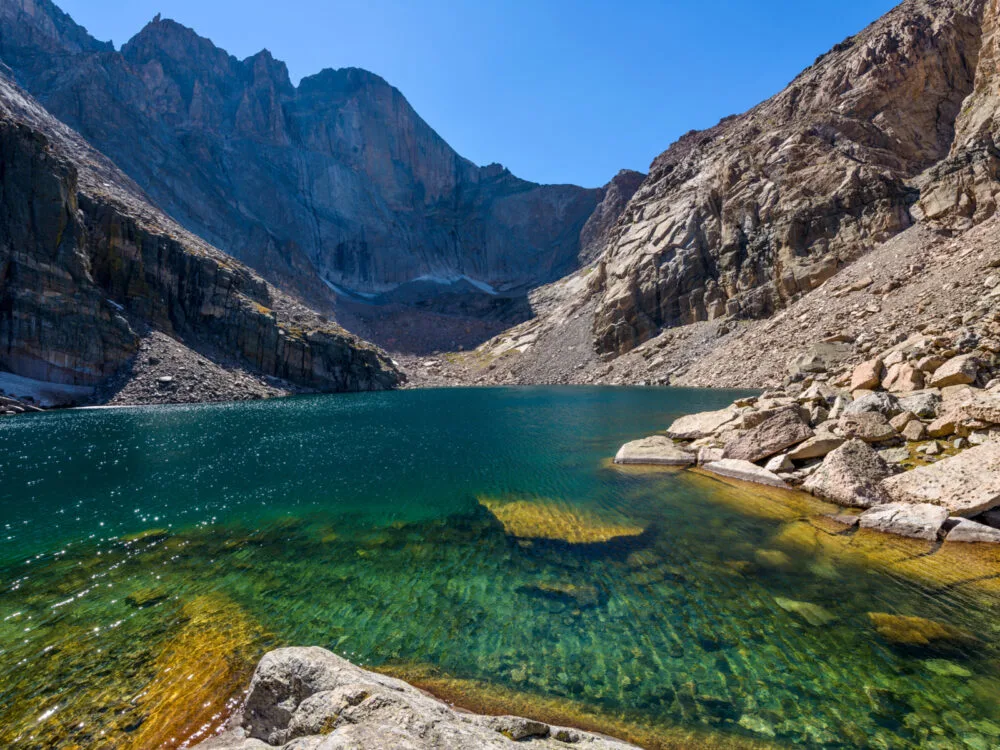 Clear green waters of the Chasm Lake at the base of Longs Peak, a part of Rocky Mountain National Park and one of the best hikes near Denver