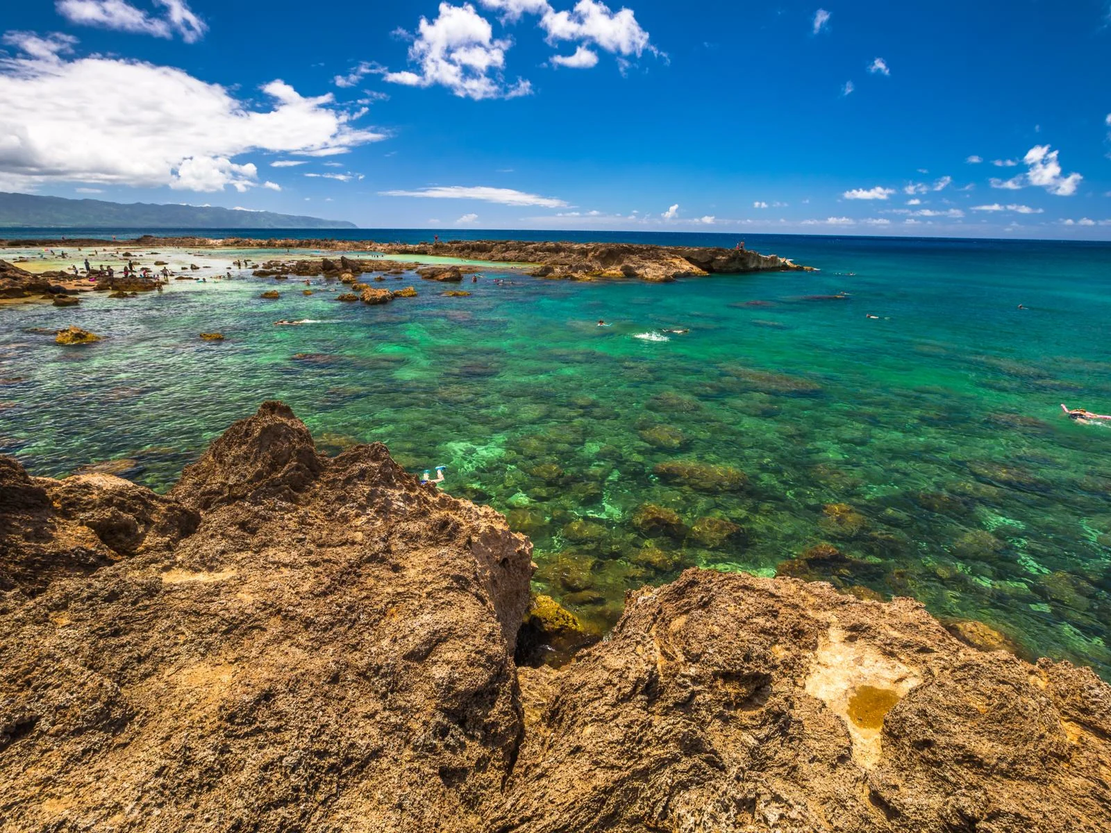 Coral reefs seen from a rock at Shark's Cove in Oahu, one of the best snorkeling spots in Hawaii, where few people are snorkeling on a clear summer day
