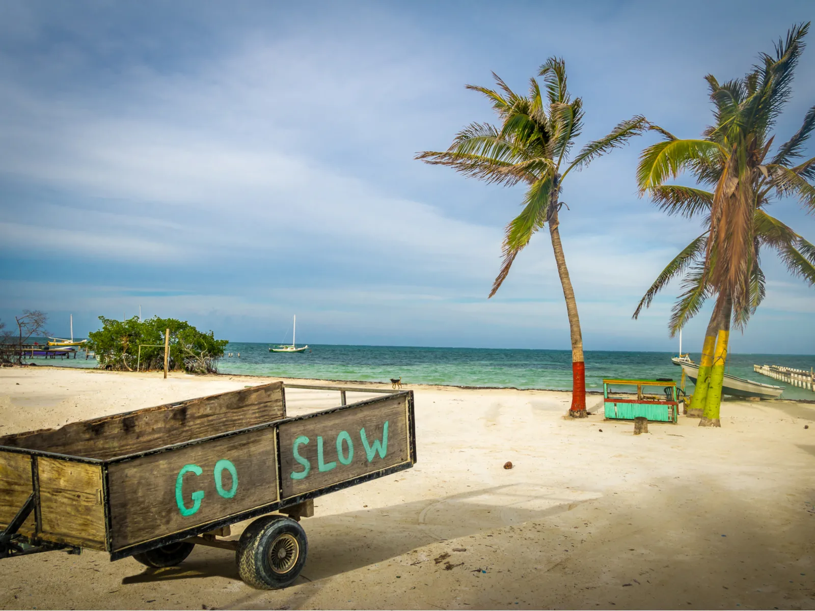 Wooden cart that says go slow pictured on a beach during the best time to visit Belize