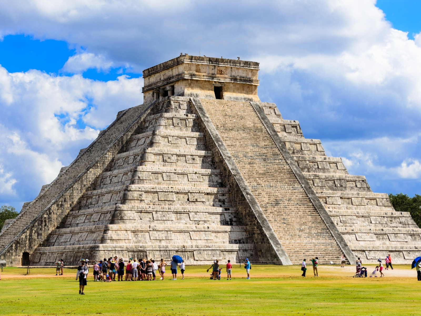 Multiple tourists taking pictures and having a great time at the foot of Chichen Itza Ruins, one of the best things to do in Cancun