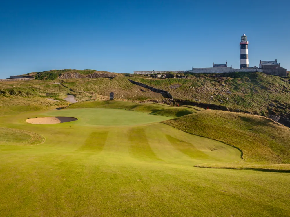 A lighthouse at the end of the vast green golf course at Old Head Golf Links, one of the best golf courses in Ireland