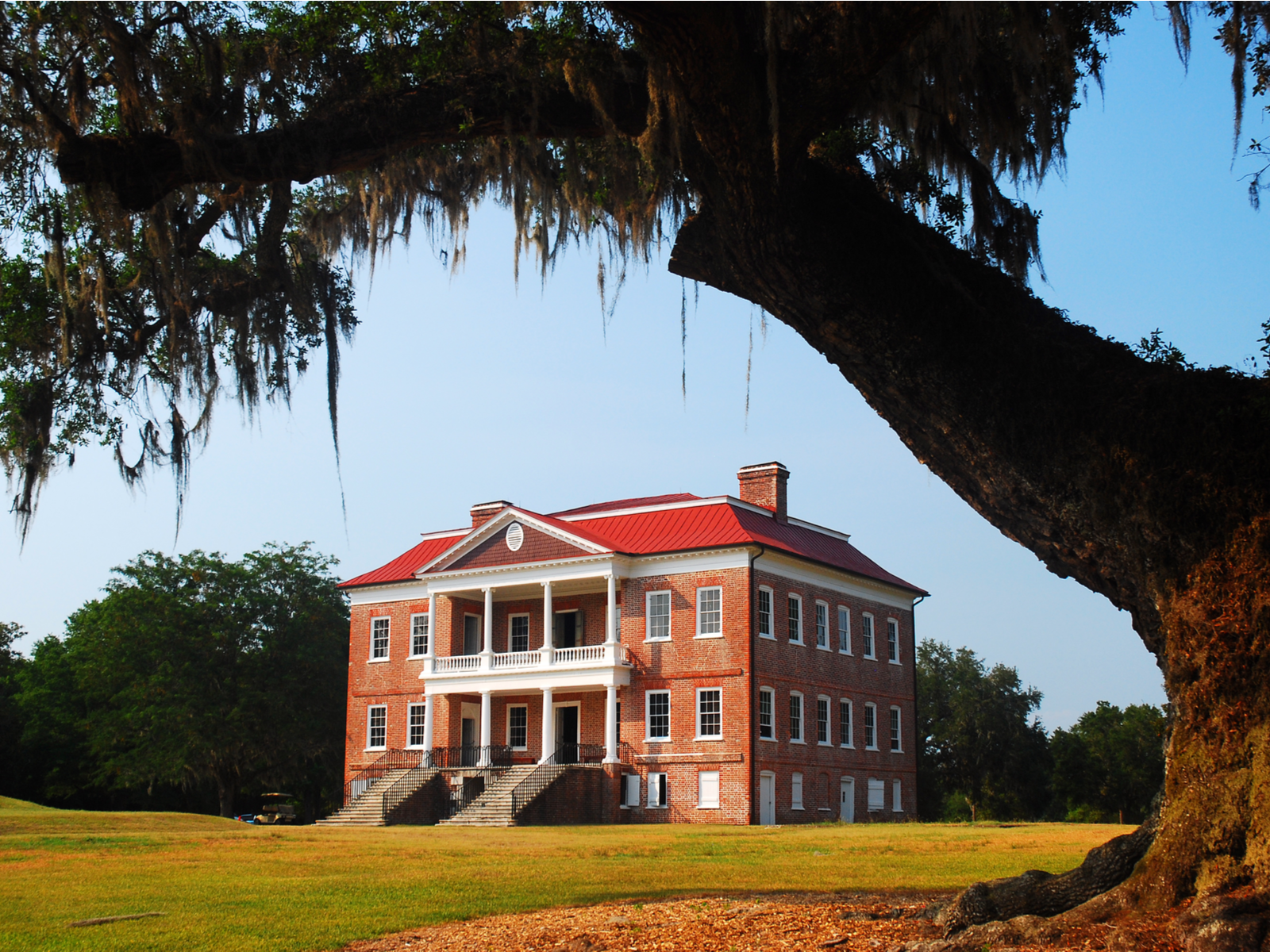 The three storey Drayton Hall at Charleston, photographed as a piece on the best South Carolina attractions, circled by a vast green lawn 