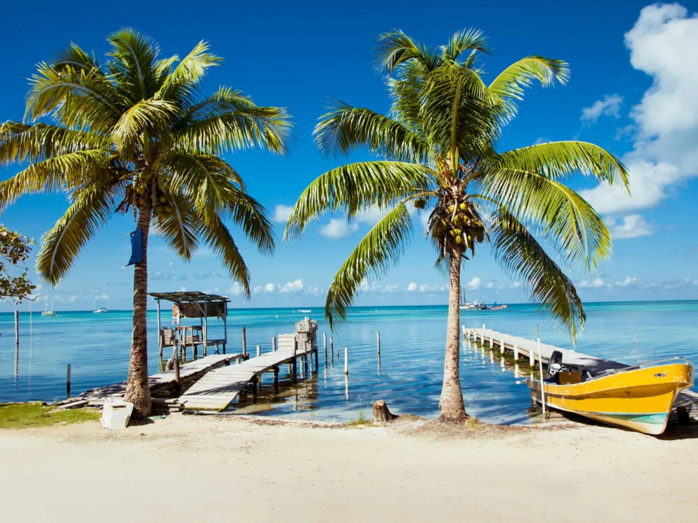 Photo of a gorgeous beach with boats and trees for a piece on Is Belize Safe