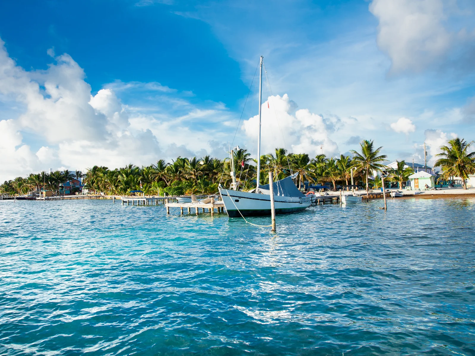 Sailboat in a bay pictured during the best time to visit Belize with blue sky and warm temps