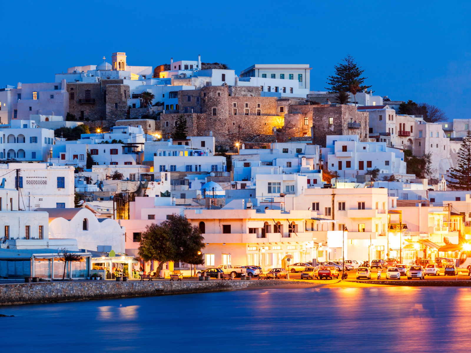 Peaceful dusk at Naxos Island, one of the best islands in Greece to visit, street lamps reflected on the still sea waters, and quiet white houses 