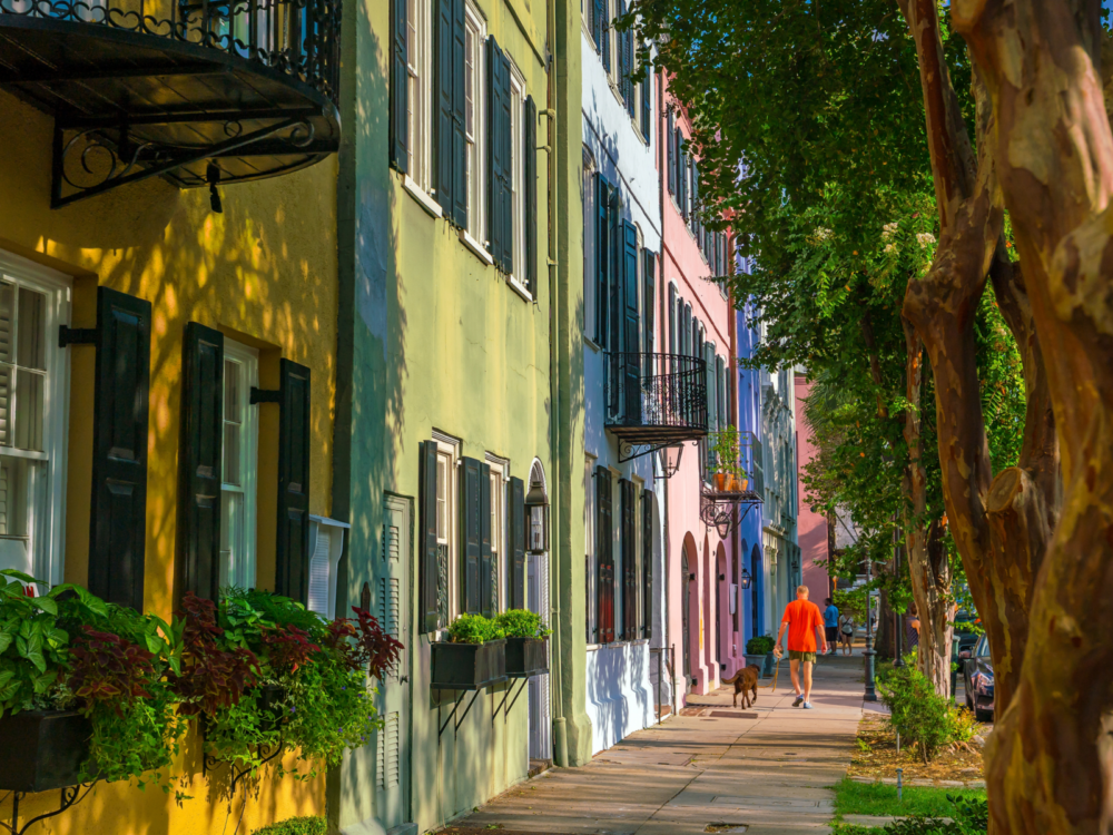 Man walking his dog down rainbow row during the Spring, the best time to visit Charleston South Carolina