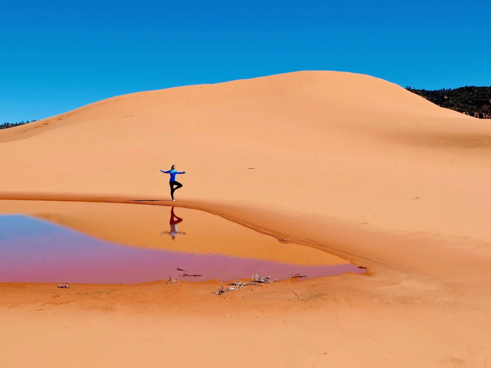 Woman doing yoga on the Coral Pink Sand Dunes State Park, one of the best places to visit in Utah