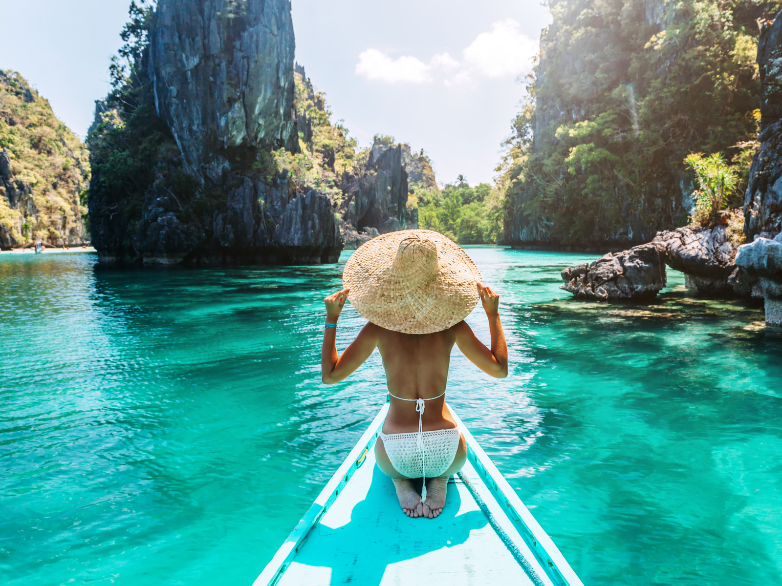 Rear view of a gorgeous woman sitting on a boat at one of the best island vacations, Palawan, Philippines