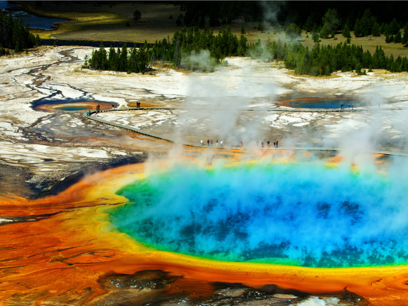 People walking on a path beside the vibrant and steamy Grand Prismatic Pool at Yellowstone National Park, one of the best things to see in Idaho