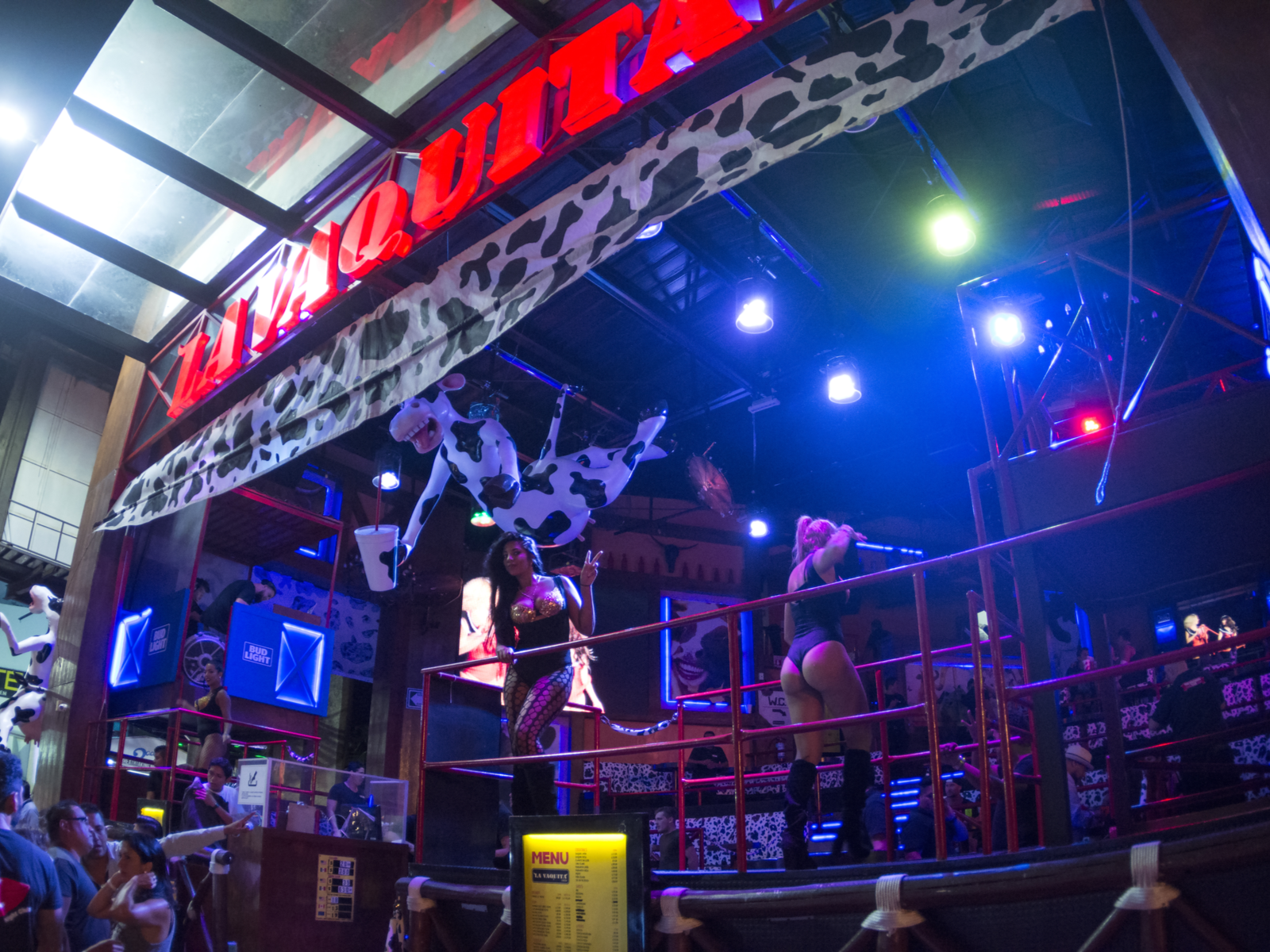Dancers entertaining customers on a platform at La Vaquita, listed as one of the best clubs in Cancun, in erotic one piece, fishnet stockings, and high-heeled boots