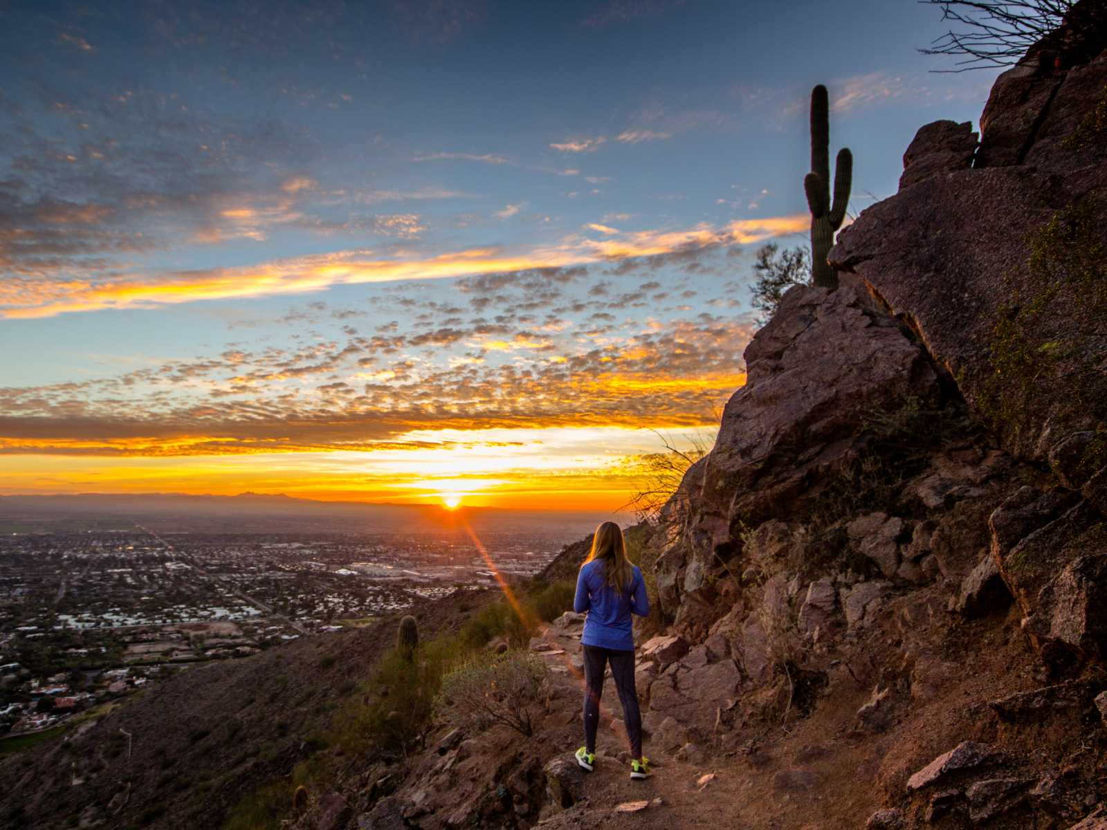 Woman watching the sunrise from Camelback mountain, one of the best things to do in Phoenix