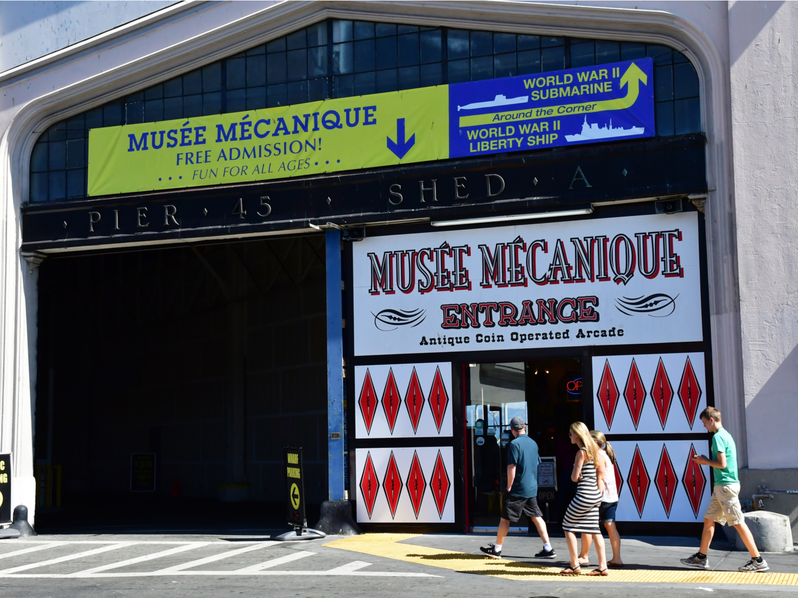 Four people seen passing by Musee Mecanique, a pick on the best places to visit in San Francisco, on a hot afternoon