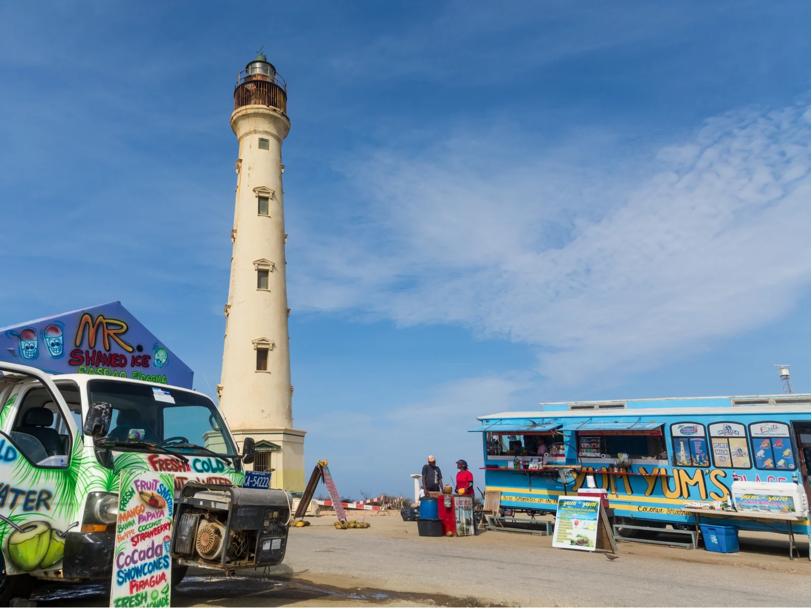 HUDISHIBANA, ARUBA pictured with a food truck and a coconut water truck outside a lighthouse for a piece on the best restaurants in Aruba