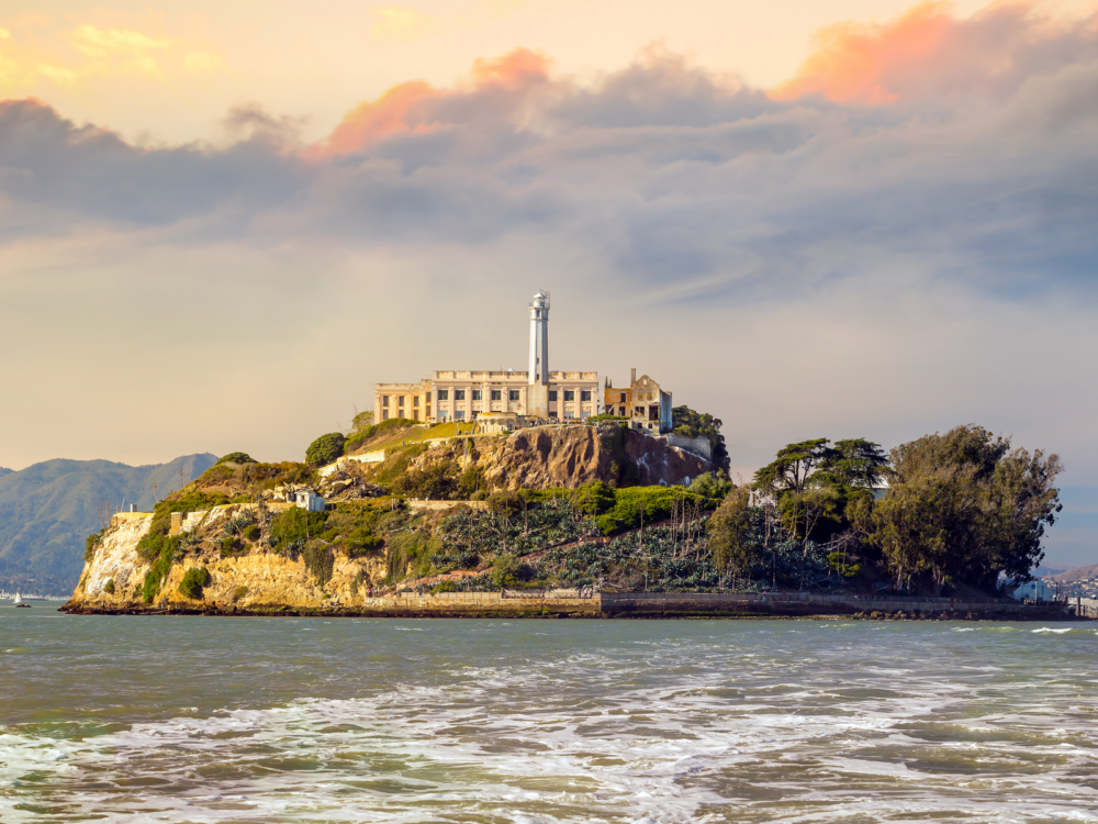 The renowned Alcatraz Island, one of the best places to visit in San Francisco, built with a tall lighthouse at the center and fortified military facility and prison surrounded by deep sea
