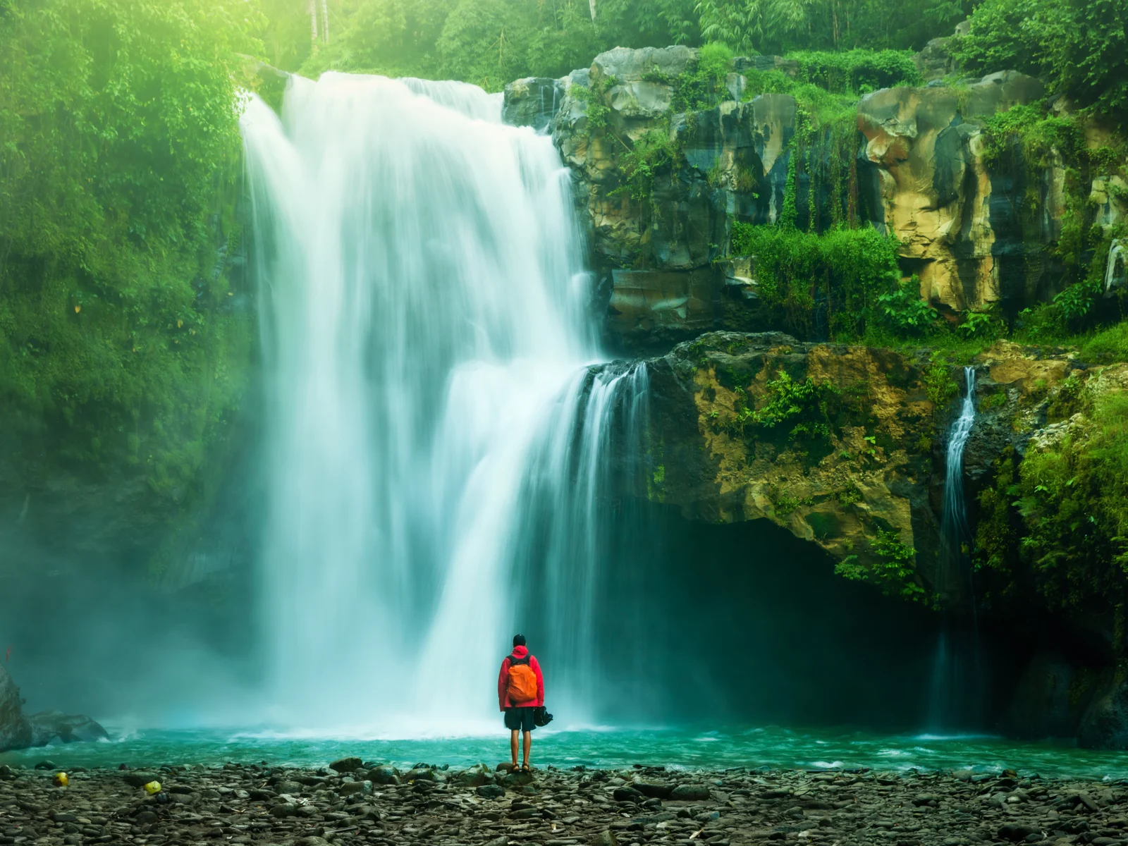 Waterfall pictured during the best time to visit brazil featuring a guy in hiking gear standing at the edge of the water