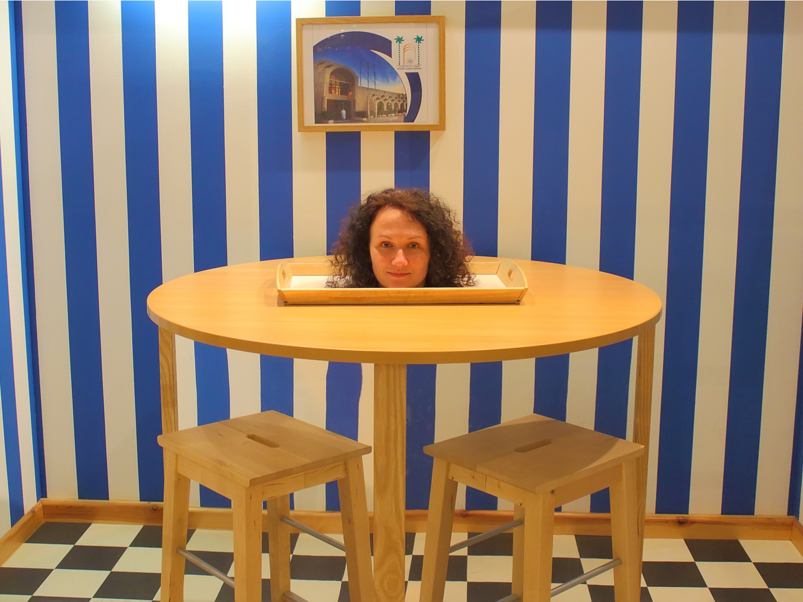 Person sticking her head up from a table in the museum of 3d illusions, one of the best things to do in San Francisco