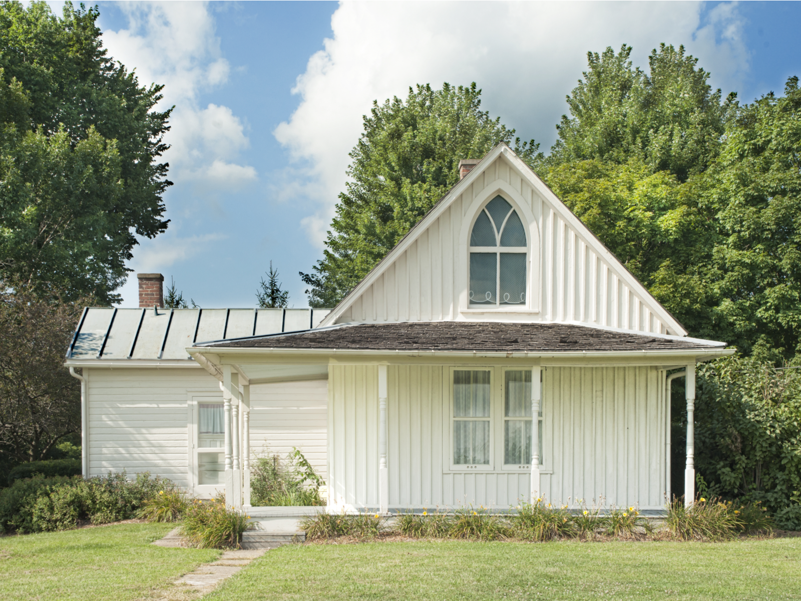 The unique architecture on American Gothic House makes it a pick for what to see in Iowa with a cream-white color exterior and a distinct upper window 