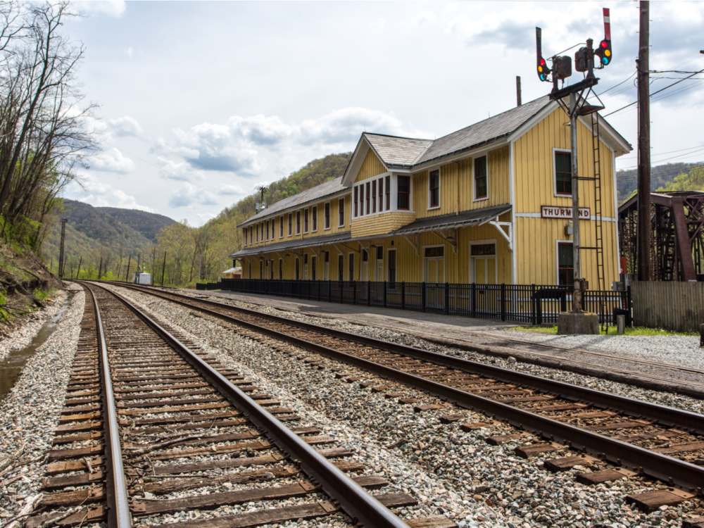 The Thurmond Train Depot, painted yellow and one of the best attractions in West Virginia, sits beside two set of train rails