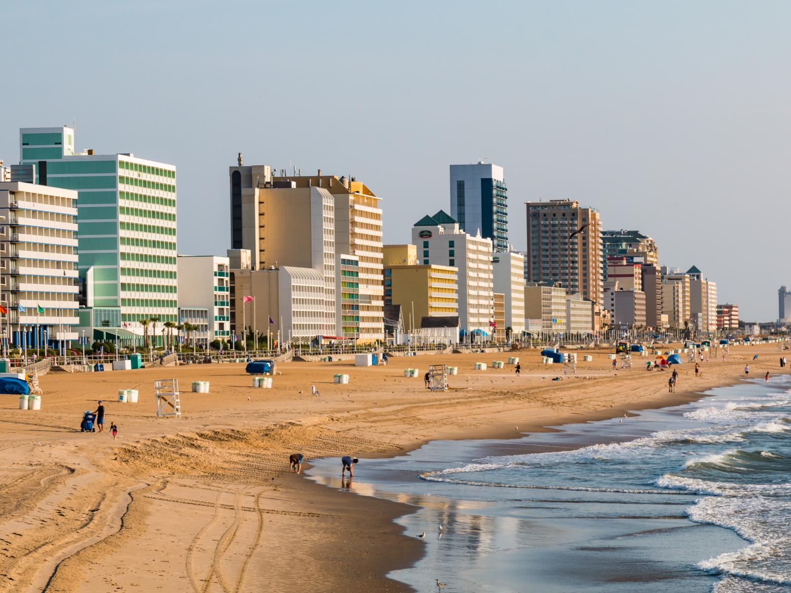 Locals walking on the shore of Virginia Beach, one of the things to do in Virginia, fronting an array of high-rise hotels