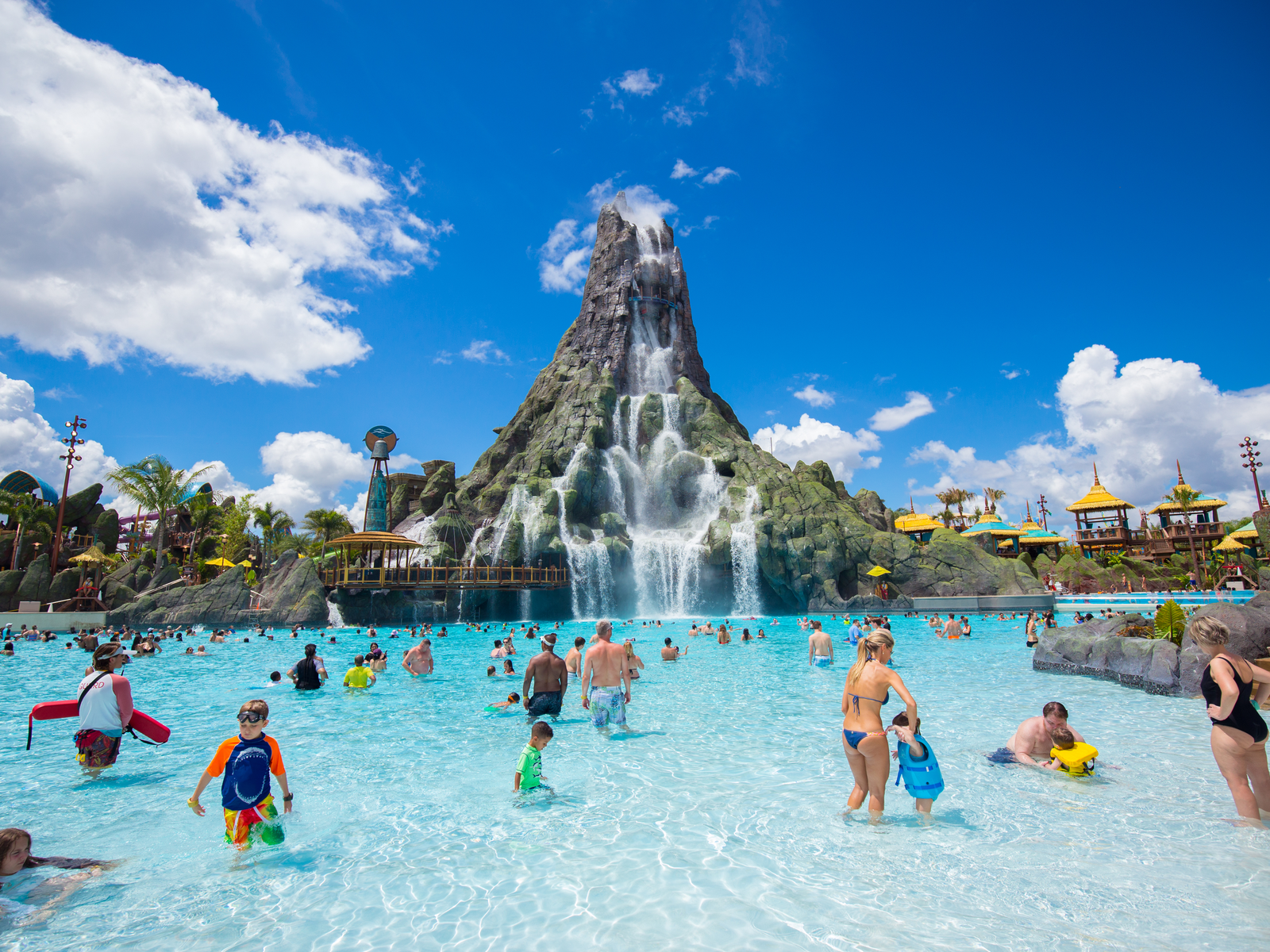 A busy sunny day at one of the best water parks in the USA, Universal's Volcano Bay in Orlando, Florida where parents are having a good time with their kids in a shallow pool