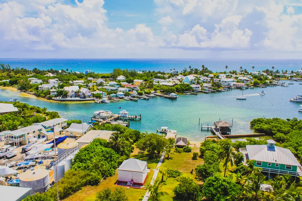 Aerial view of Hope Town harbour, as seen from the Elbow Reef Lighthouse, in Abaco, one of the safest islands in the Caribbean, with colorful vegetation, buildings, and boats below
