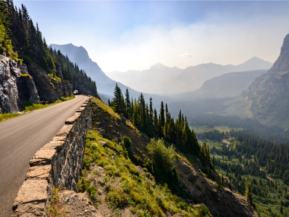 Cool tunnel road pictured during the best time to visit Glacier National Park, with a smoky horizon obscuring most mountains