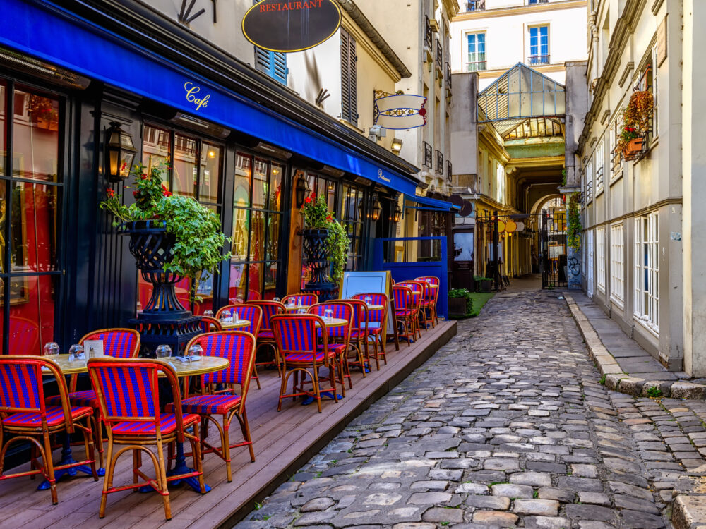 Neat view of a cafe on a corner of a brick-lined street in Paris