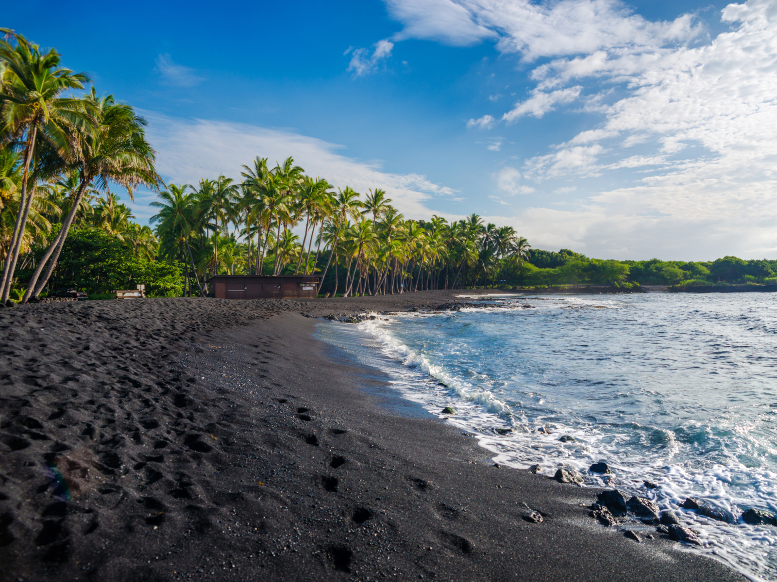 Black sand beach pictured during the best time to visit the Big Island off the coast of Punaluu