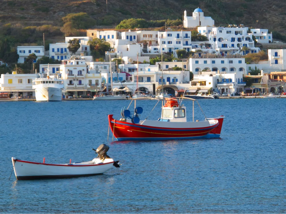 Two small fishing boats idling offshore the Amorgos Island, A piece on the best places to visit in Greece, seen an area of white structures near the coast