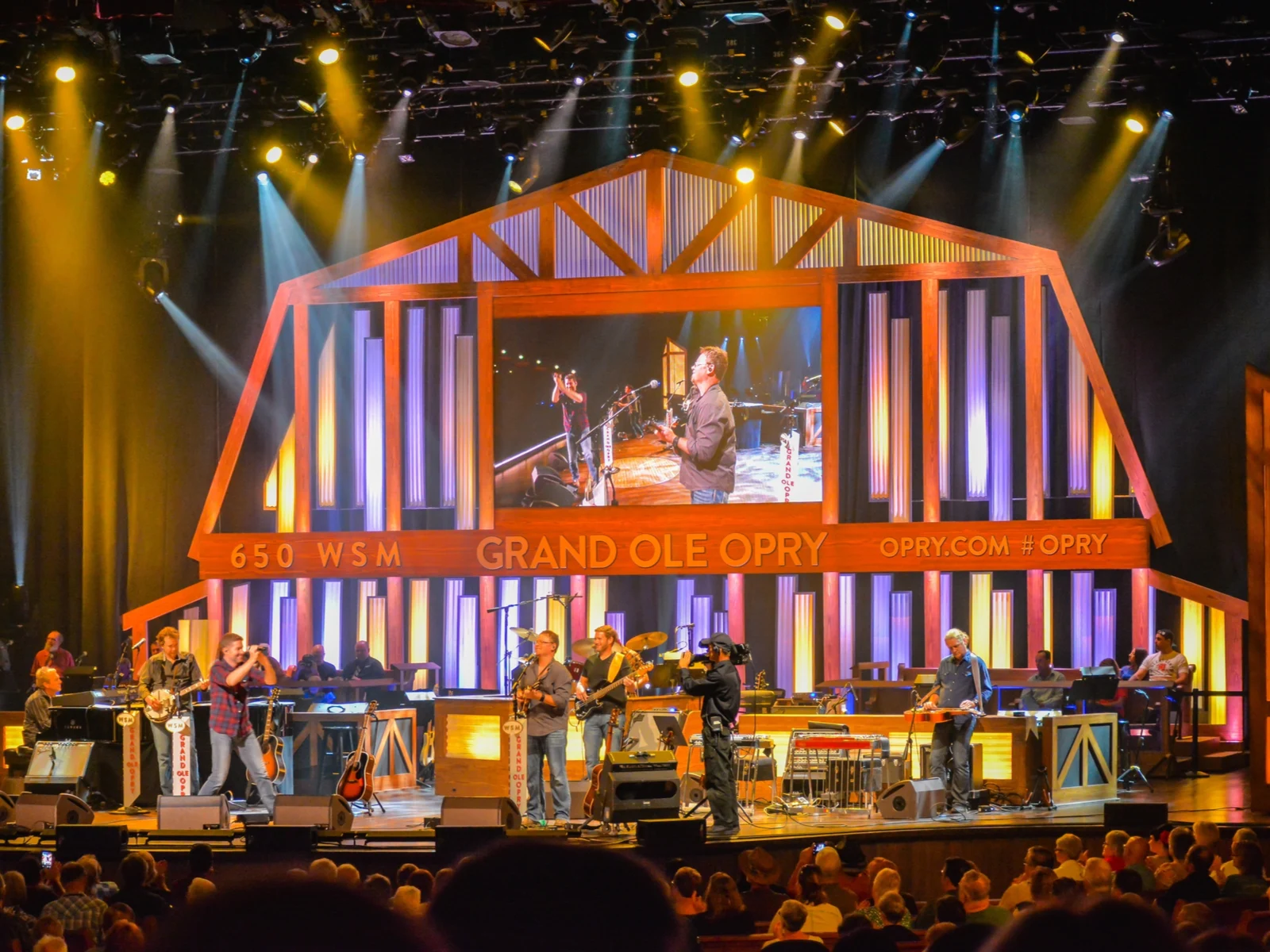 Live bands performing on the stage of Grand Ole Opry, brightly lit with white and yellow, as one of the best things to do in Tennessee 