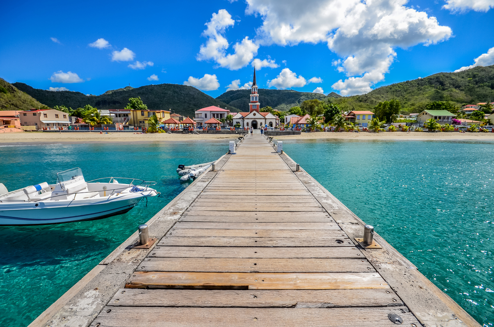 Picturesque view of the coastal town of Martinique, taken from the end of the pier looking toward the beach and church for a guide to the safest islands in the Caribbean