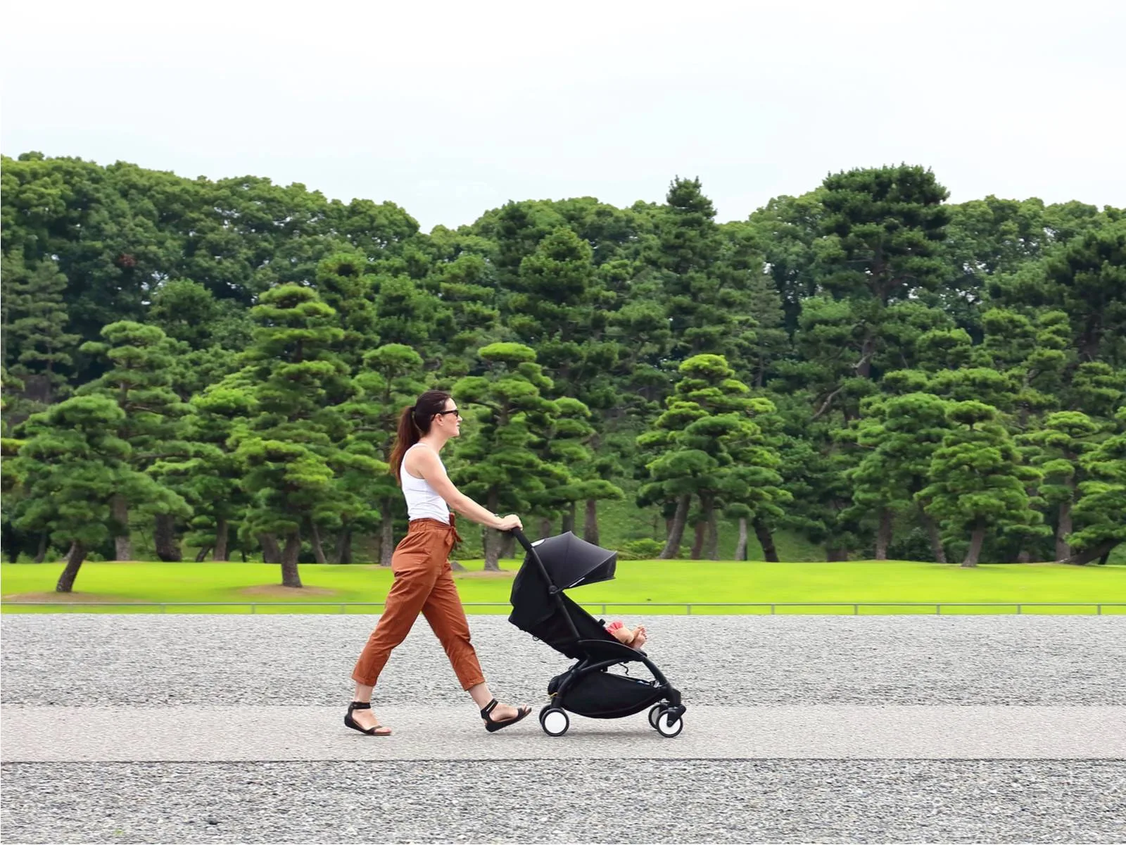 Woman using the best travel stroller on a well-manicured road in a park in Tokyo