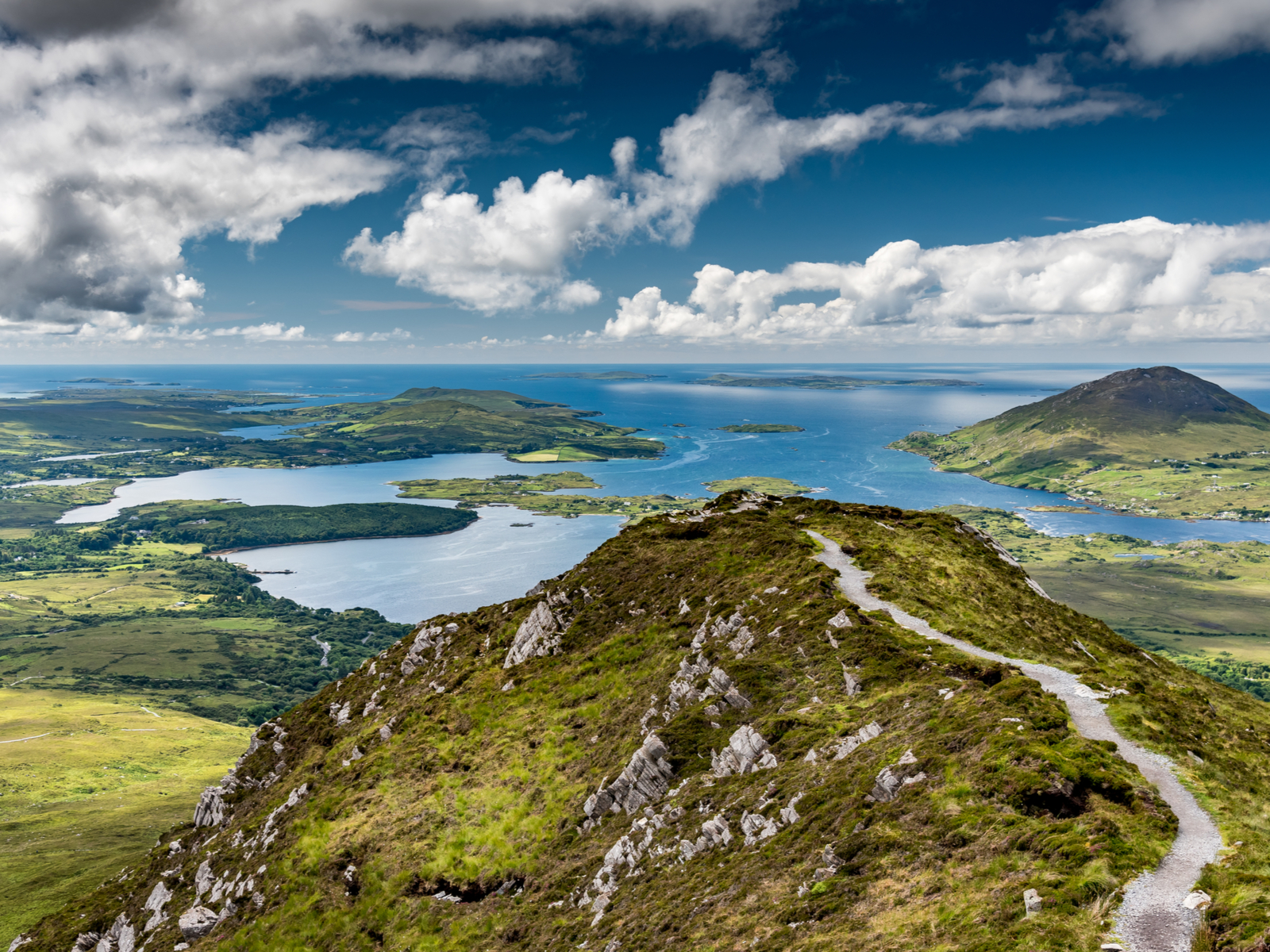 Trail at Diamond Hill in Connemara National Park, one of the best hikes in Ireland, overlooking green pastures and a blue ocean