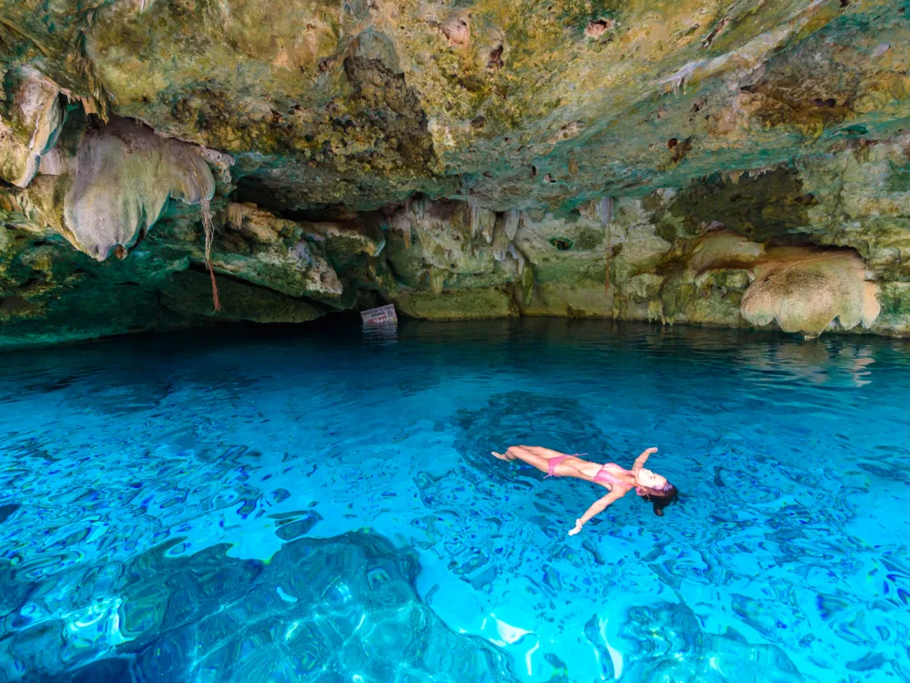 A woman wearing her swimwear swimming at the crystalline water at Quintana Roo’s Underground Stalactite Rivers, one of the best things to do in Cancun