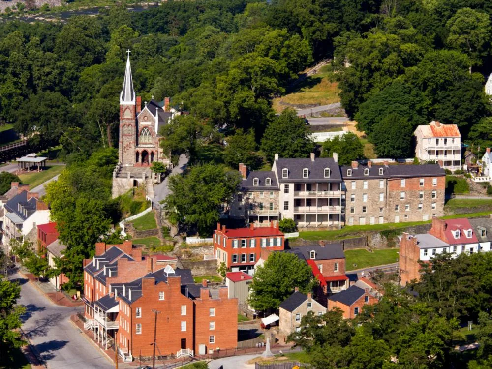 Aerial view on Harper’s Ferry's classic buildings, one of the best attractions in West Virginia, next to an area of green trees
