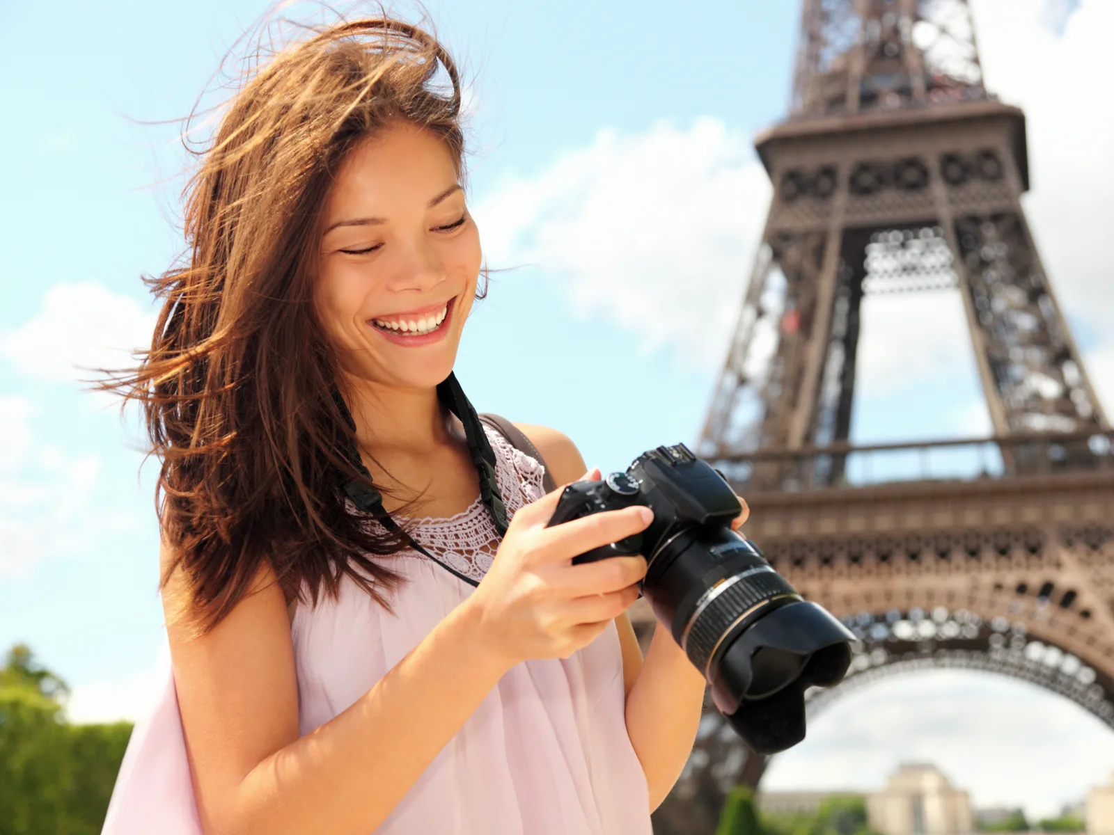 Woman using one of the best travel cameras to photograph the Eiffel Tower