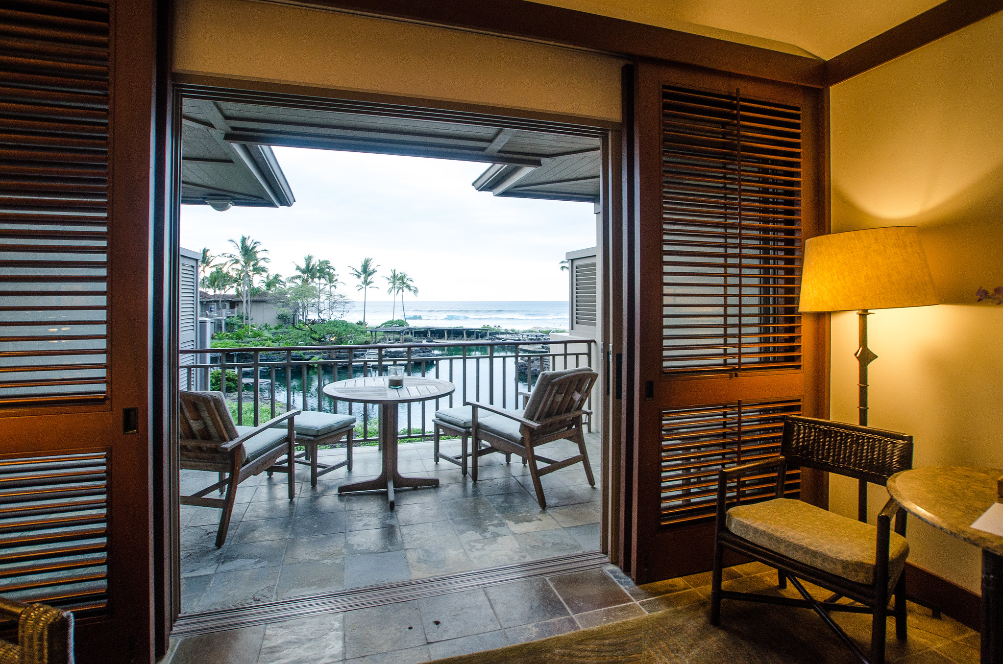 Lovely open view of the coast at an elegant room with empty chairs and a small rounded table in Four Seasons Resort Hotel in Hualalai, one of the best hotels in Kona, Hawaii