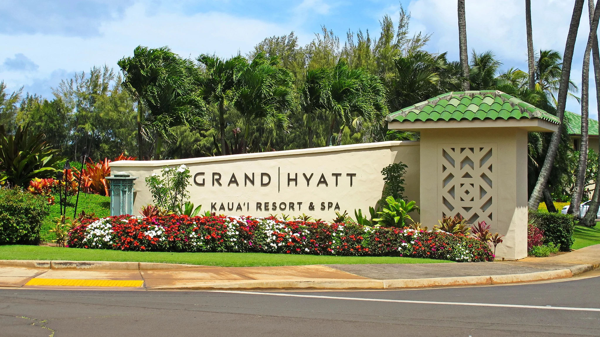 Vibrant flowers below the sign of Grand Hyatt Kauai Resort & Spa, a piece on the best hotels in Kauai