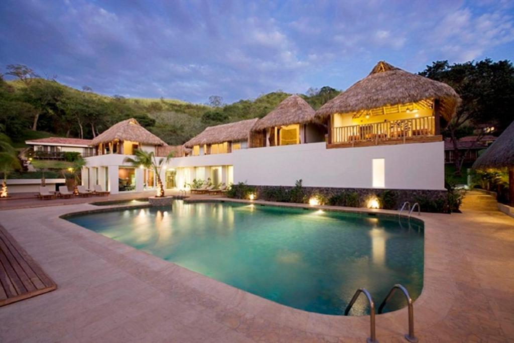 Pool and villas with thatched roof at the Secrets Papagayo All Inclusive, one of our picks for the best all-inclusive resorts in Costa Rica