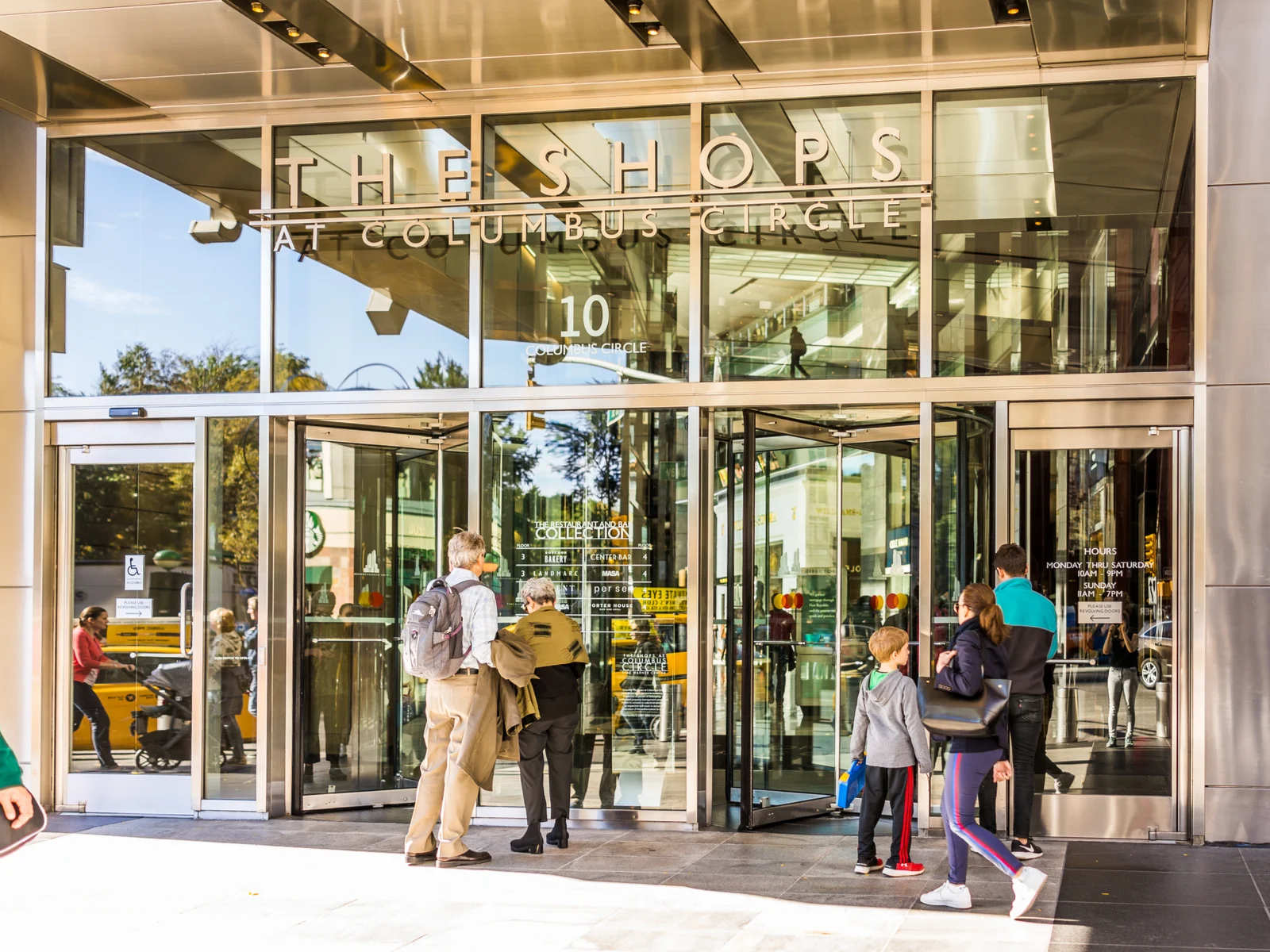 Shoppers going in through the revolving door at the entrance of The Shops at Columbus Circle in New York, considered one of the best malls in America