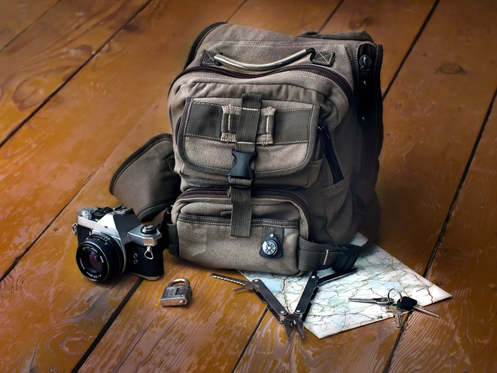 Bag and accessories on a table next to a map and a camera