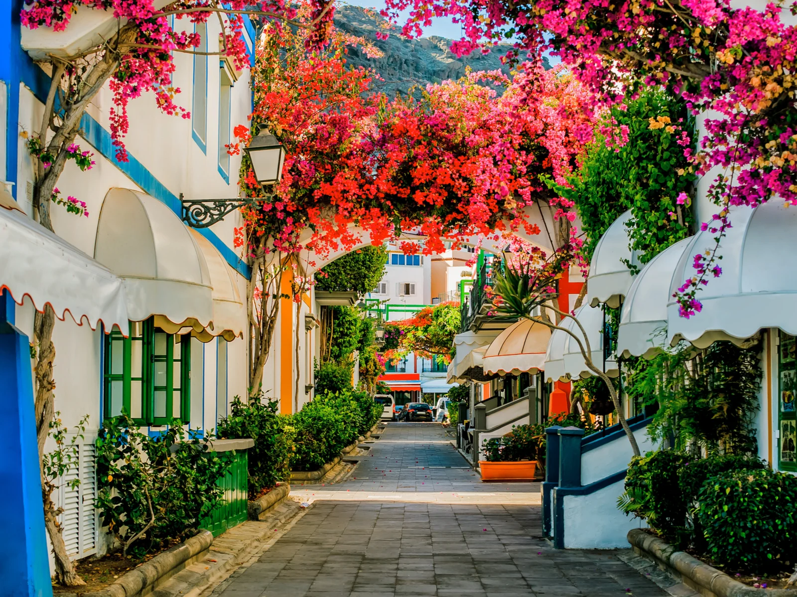 During the least busy time to visit Spain, the Puerto de Mogan town is pictured from an alleyway with brightly colored buildings and shutters