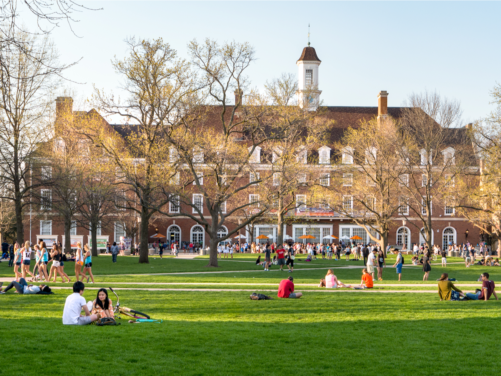 Students walking and sitting at the clean green lawn during Autumn at the University of Illinois, one of the most beautiful college campuses