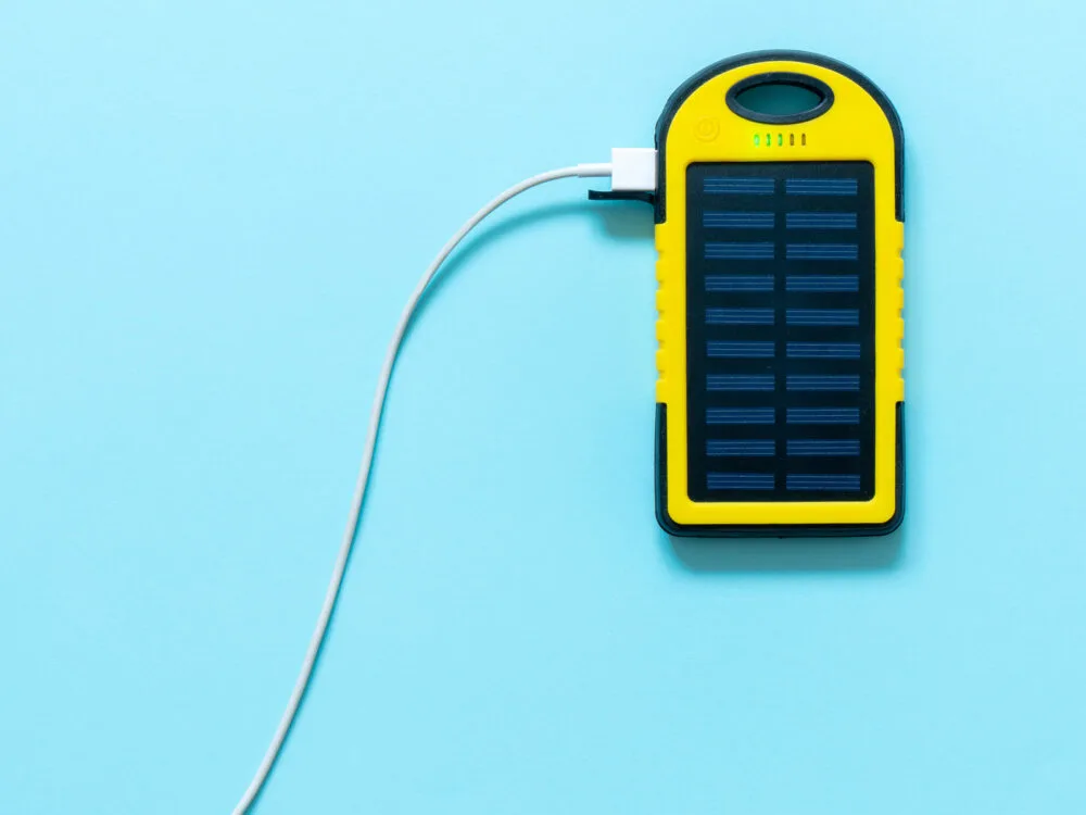 Yellow and black portable solar power bank charging an unpictured device on a blue background