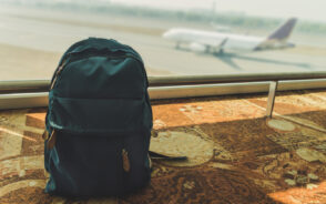 Photo of one of the best carry-on backpacks sitting on the floor next to an airport window overlooking the taxiway