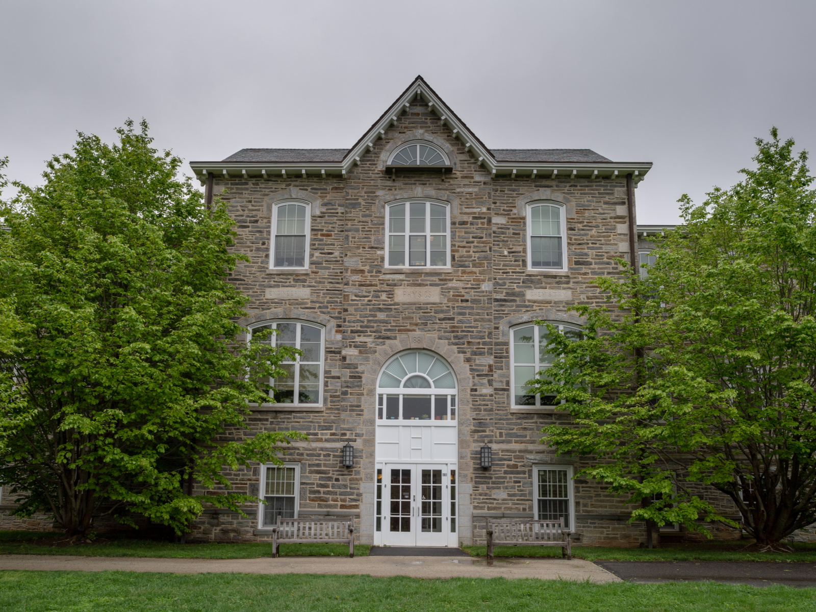 An old Physic building with glass windows and two benches in front at Swarthmore College in Pennsylvania, one of the most beautiful college campuses